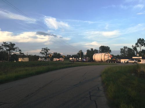 An oversize load moving along a quiet road as the light fades