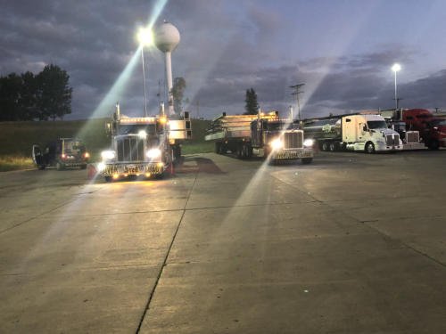FT&L tractors staged after dark with headlights and work lights illuminating the yard