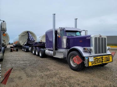 Front three-quarter view of a purple FT&L Peterbilt under load