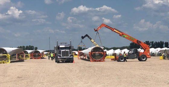 Components staged in a laydown yard beside a crawler crane